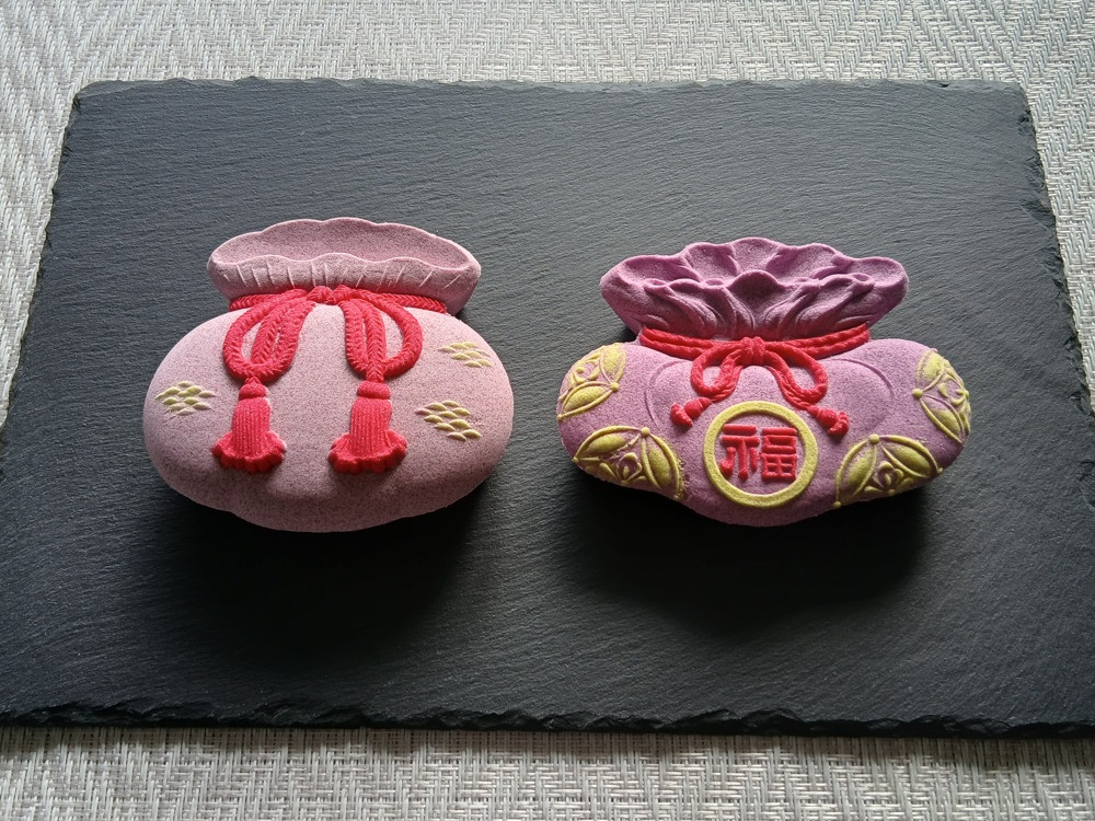 巾着のかたちをした落雁。左に福結、右に黄金結びの祝い菓子