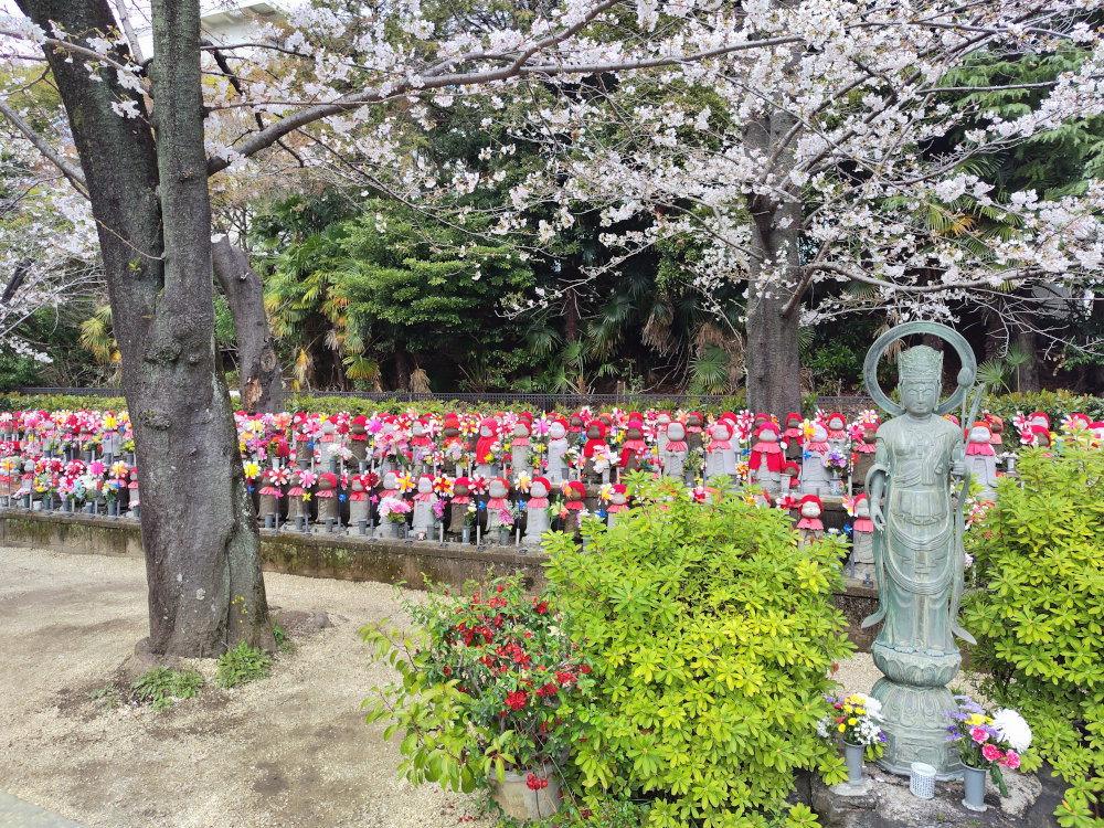 風に揺れる風車と子供地蔵の風景