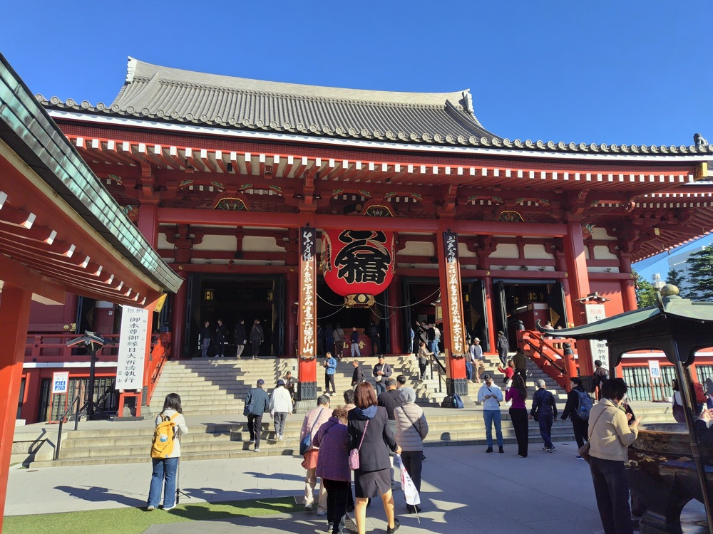 浅草寺本堂、朱塗りの荘厳な建物で静かに祈る人々
